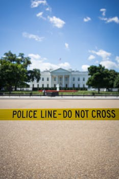 Police tape in front of the White House, Washington, DC, under a clear blue sky.